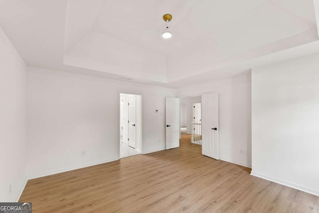 3878 Brookside Pkwy, Decatur, GA 30034 - unfurnished bedroom with a tray ceiling, light wood-type flooring, and baseboards