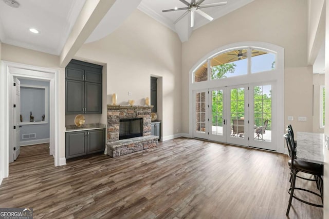 7519 Waterview Cv, Douglasville, GA 30135 - unfurnished living room featuring ceiling fan, dark wood-style flooring, a stone fireplace, a towering ceiling, and baseboards