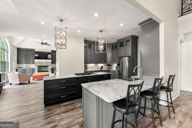 7519 Waterview Cv, Douglasville, GA 30135 - kitchen featuring a chandelier, a peninsula, appliances with stainless steel finishes, light stone counters, and light wood-type flooring