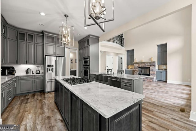7519 Waterview Cv, Douglasville, GA 30135 - kitchen featuring a chandelier, stainless steel appliances, a kitchen island, a stone fireplace, and light stone countertops