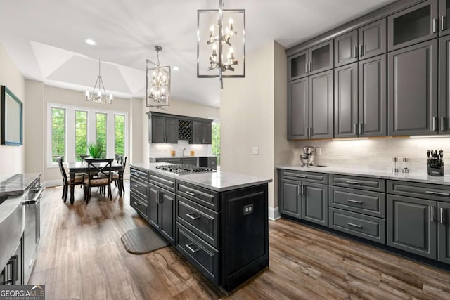 7519 Waterview Cv, Douglasville, GA 30135 - kitchen with a chandelier, stainless steel gas cooktop, dark wood finished floors, backsplash, and a center island