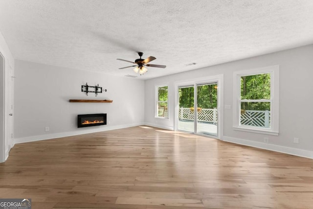 4690 Giddon Martin Rd, Gainesville, GA 30506 - unfurnished living room with a textured ceiling, wood-type flooring, a ceiling fan, a glass covered fireplace, and baseboards