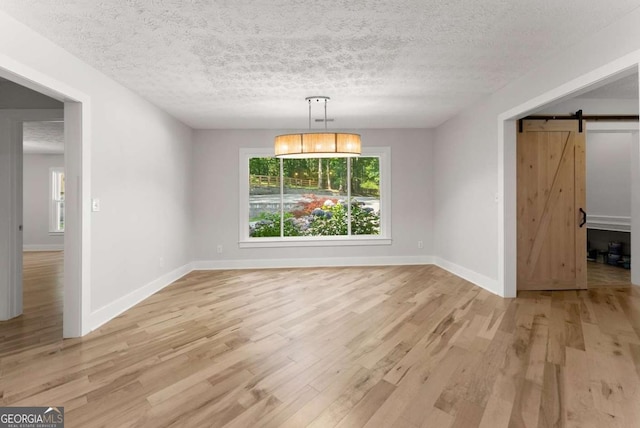 4690 Giddon Martin Rd, Gainesville, GA 30506 - unfurnished dining area with a barn door, light wood-style floors, baseboards, and a textured ceiling