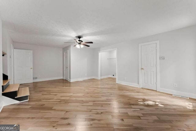 4690 Giddon Martin Rd, Gainesville, GA 30506 - unfurnished living room featuring ceiling fan, light wood-style flooring, baseboards, and a textured ceiling
