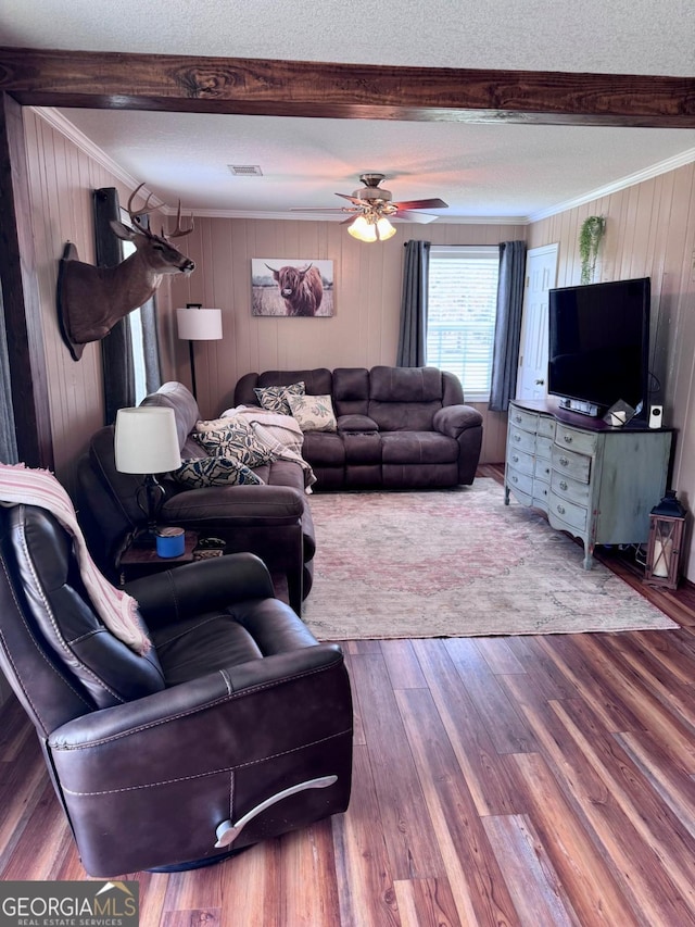 309 Ralph Wommack Rd, Hazlehurst, GA 31539 - living room with beam ceiling, crown molding, wood walls, wood finished floors, and a ceiling fan