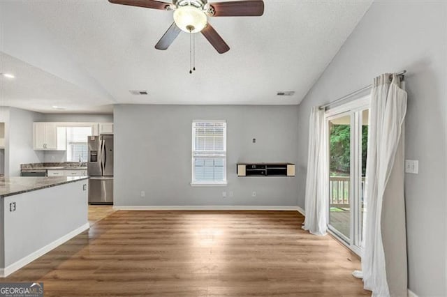 713 Fairfield Dr, Peachtree City, GA 30269 - kitchen with stainless steel refrigerator with ice dispenser, lofted ceiling, white cabinetry, plenty of natural light, and light wood-style floors