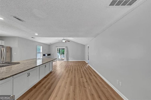 713 Fairfield Dr, Peachtree City, GA 30269 - unfurnished living room featuring a textured ceiling, light wood-style floors, ceiling fan, baseboards, and lofted ceiling