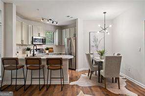 821 Ralph Mcgill Blvd NE Unit 2219, Atlanta, GA 30306 - kitchen with stainless steel appliances, a peninsula, a kitchen bar, light countertops, and dark wood-type flooring