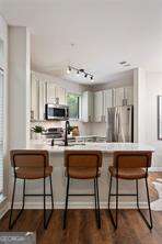 821 Ralph Mcgill Blvd NE Unit 2219, Atlanta, GA 30306 - kitchen featuring appliances with stainless steel finishes, a kitchen breakfast bar, dark wood-style floors, and light countertops