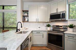 821 Ralph Mcgill Blvd NE Unit 2219, Atlanta, GA 30306 - kitchen featuring stainless steel appliances, a sink, open shelves, light stone counters, and wood finished floors