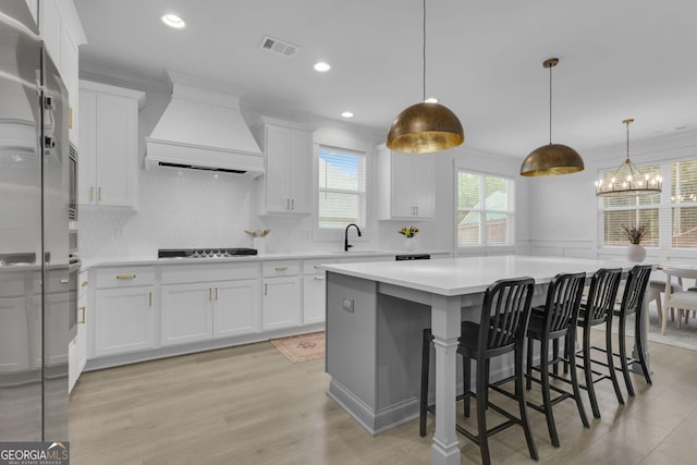 155 Lapis Lake Pt, Fayetteville, GA 30215 - kitchen featuring premium range hood, cooktop, a sink, light countertops, and a center island
