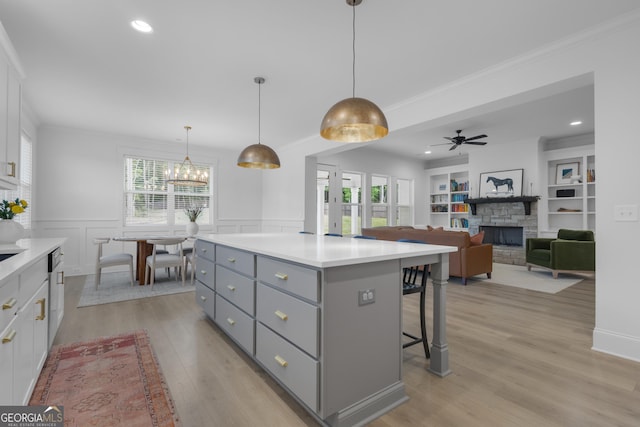 155 Lapis Lake Pt, Fayetteville, GA 30215 - kitchen with gray cabinets, ornamental molding, a stone fireplace, a breakfast bar, and a center island