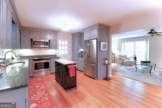3320 Bryant Ln, Marietta, GA 30066 - kitchen with stainless steel appliances, gray cabinetry, light wood-style floors, ceiling fan, and decorative backsplash