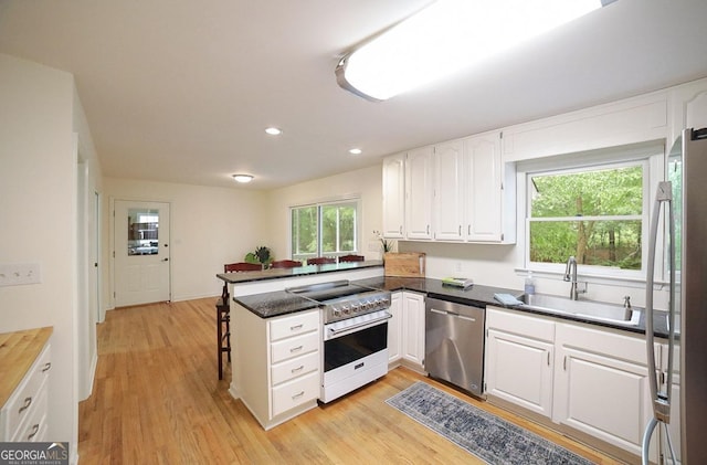 1111 Creekshore Dr, Athens, GA 30606 - kitchen with stainless steel appliances, a sink, a peninsula, white cabinetry, and recessed lighting