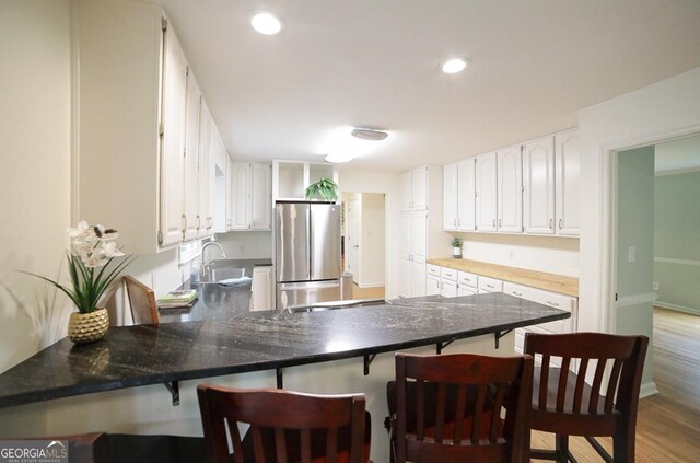 1111 Creekshore Dr, Athens, GA 30606 - kitchen featuring freestanding refrigerator, a peninsula, white cabinetry, a sink, and open shelves