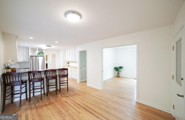 1111 Creekshore Dr, Athens, GA 30606 - kitchen featuring freestanding refrigerator, a kitchen breakfast bar, a peninsula, white cabinets, and recessed lighting