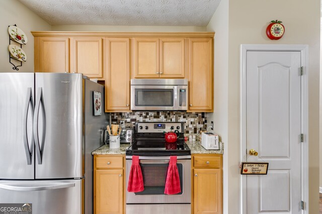 129 Onyx Ct, Carrollton, GA 30116 - kitchen featuring appliances with stainless steel finishes, decorative backsplash, light stone countertops, and light brown cabinetry