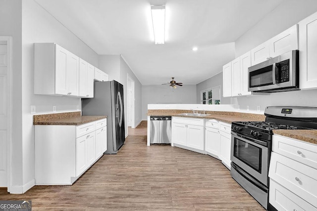 6708 Thornwood Ct, Flowery Branch, GA 30542 - kitchen with stainless steel appliances, a sink, a peninsula, a ceiling fan, and white cabinetry