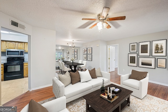 514 Mcgill Pl NE, Atlanta, GA 30312 - living room featuring a ceiling fan, light wood-type flooring, a chandelier, a textured ceiling, and baseboards