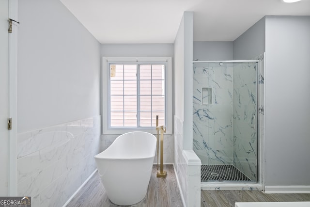 984 Wenham Ln, Lawrenceville, GA 30044 - bathroom featuring a marble finish shower, a freestanding tub, wood finished floors, tile walls, and wainscoting