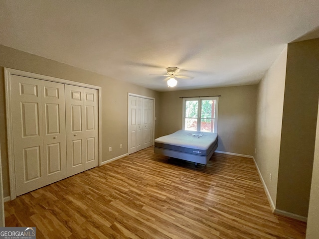 555 Barker Trail Rd, Cleveland, GA 30528 - unfurnished bedroom featuring two closets, wood finished floors, baseboards, and a ceiling fan