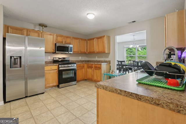 7813 Newbury Dr, Jonesboro, GA 30236 - kitchen featuring stainless steel appliances, a chandelier, light floors, and a textured ceiling