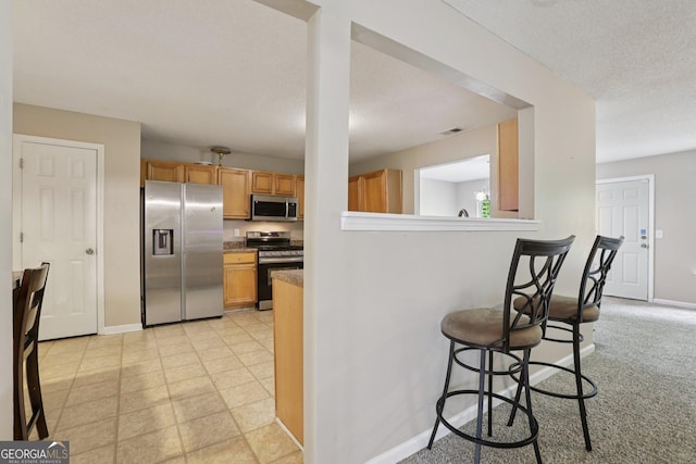 7813 Newbury Dr, Jonesboro, GA 30236 - kitchen with appliances with stainless steel finishes, a kitchen breakfast bar, baseboards, and a textured ceiling