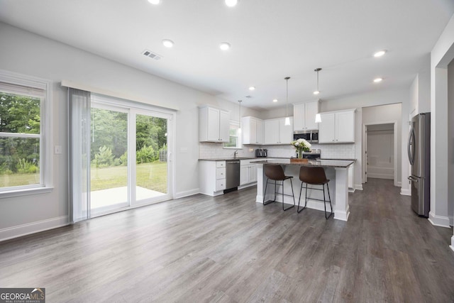 9929 Long Leaf Pine Dr, Midland, GA 31820 - kitchen featuring appliances with stainless steel finishes, a kitchen island, decorative backsplash, a breakfast bar area, and dark wood-style floors