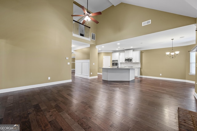 108 Donovan Ave, Locust Grove, GA 30248 - unfurnished living room featuring ceiling fan, a chandelier, dark wood-style flooring, high vaulted ceiling, and baseboards