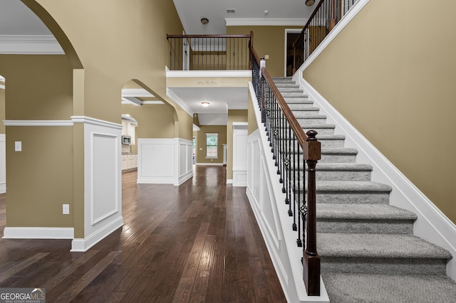 108 Donovan Ave, Locust Grove, GA 30248 - foyer featuring arched walkways, dark wood-style floors, a high ceiling, stairway, and a wainscoted wall