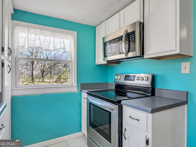 927 Dean Patrick Rd, Locust Grove, GA 30248 - kitchen with stainless steel appliances, white cabinetry, light tile patterned flooring, a textured ceiling, and dark countertops