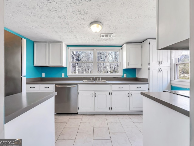 927 Dean Patrick Rd, Locust Grove, GA 30248 - kitchen with dishwasher, a sink, healthy amount of natural light, a textured ceiling, and white cabinets
