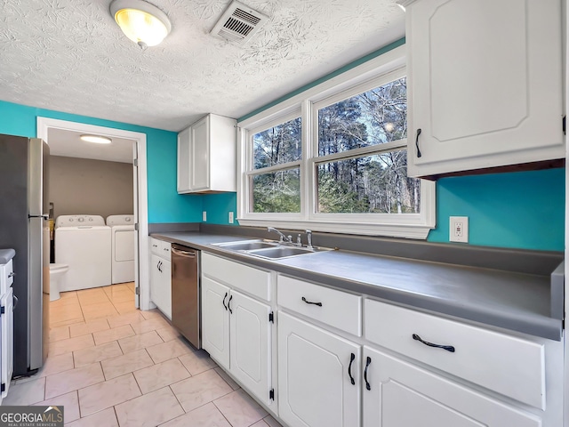 927 Dean Patrick Rd, Locust Grove, GA 30248 - kitchen with independent washer and dryer, stainless steel appliances, a sink, white cabinets, and plenty of natural light