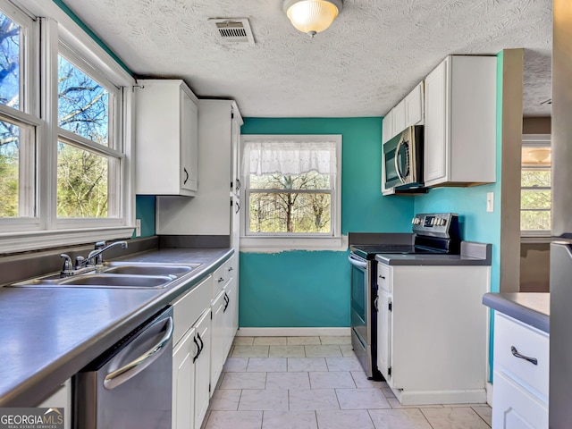 927 Dean Patrick Rd, Locust Grove, GA 30248 - kitchen featuring stainless steel appliances, a sink, white cabinetry, a textured ceiling, and baseboards