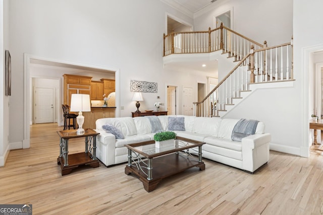 952 Moores Walk Ln, Suwanee, GA 30024 - living room featuring a towering ceiling, light wood-style floors, stairs, crown molding, and baseboards