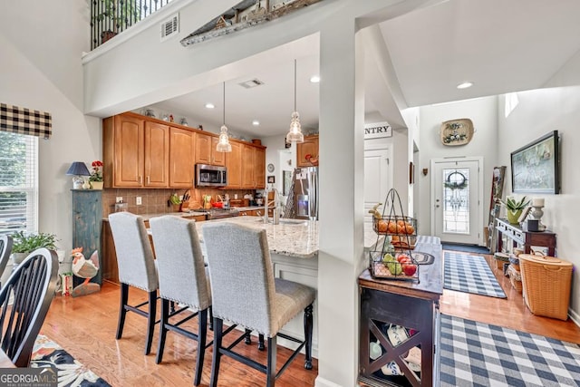 7891 Brass Lantern Dr, Flowery Branch, GA 30542 - kitchen featuring stainless steel appliances, light wood-style floors, a kitchen bar, light stone counters, and recessed lighting