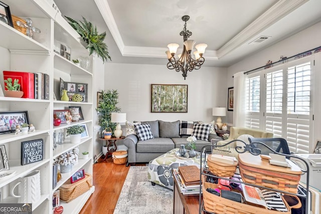 7891 Brass Lantern Dr, Flowery Branch, GA 30542 - living area featuring crown molding, a chandelier, a raised ceiling, and wood finished floors