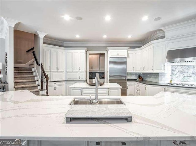 8957 Old Southwick Pass, Johns Creek, GA 30022 - kitchen featuring stainless steel appliances, a sink, ventilation hood, white cabinetry, and ornamental molding