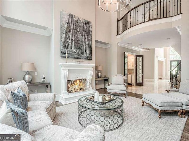 8957 Old Southwick Pass, Johns Creek, GA 30022 - living area featuring a towering ceiling, ornamental molding, a warm lit fireplace, and baseboards