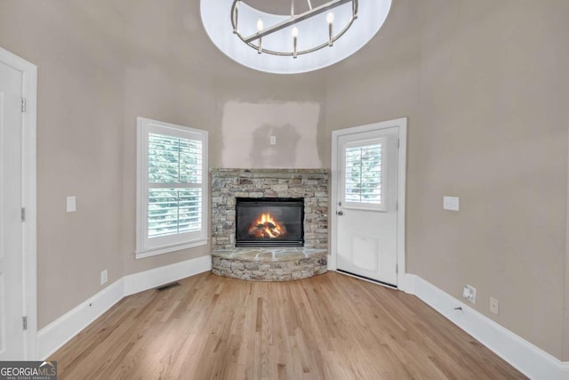 3451 Falls Branch Ct, Buford, GA 30519 - unfurnished living room with plenty of natural light, a stone fireplace, wood finished floors, and baseboards