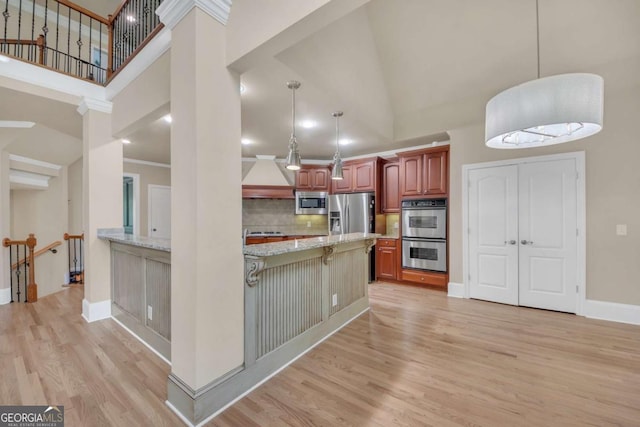 3451 Falls Branch Ct, Buford, GA 30519 - kitchen with appliances with stainless steel finishes, high vaulted ceiling, light wood-style floors, custom range hood, and a kitchen breakfast bar