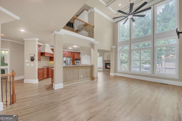 3451 Falls Branch Ct, Buford, GA 30519 - unfurnished living room featuring ornamental molding, a towering ceiling, ceiling fan, baseboards, and light wood-style floors