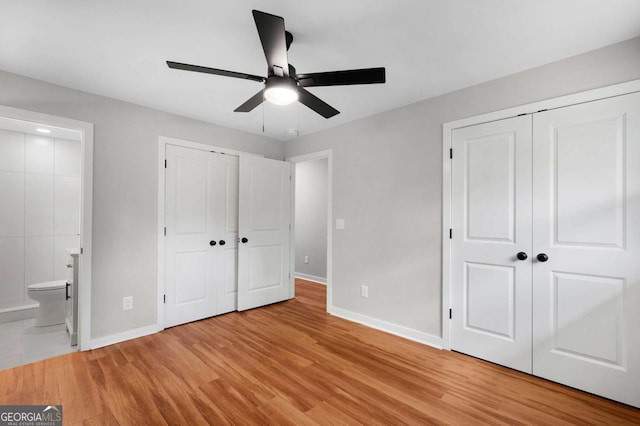 162 Langston Rd NE, Calhoun, GA 30701 - unfurnished bedroom with baseboards, multiple closets, light wood-style flooring, connected bathroom, and ceiling fan