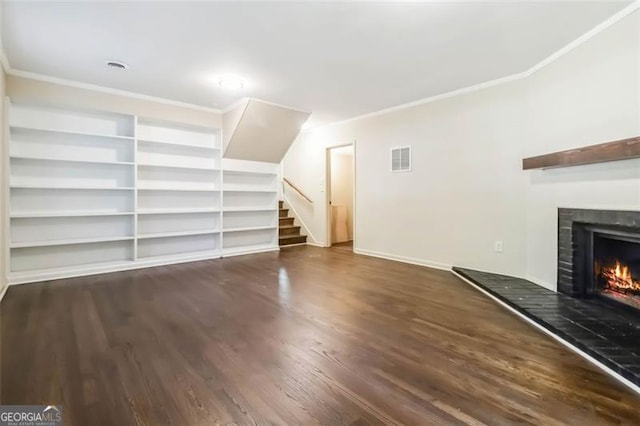 6192 Holiday Blvd, Forest Park, GA 30297 - unfurnished living room featuring ornamental molding, a warm lit fireplace, wood finished floors, stairs, and built in shelves