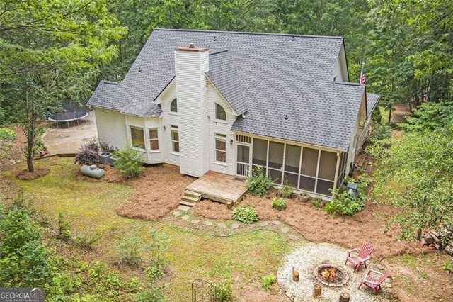 83 Shipp, Hiram, GA 30141 - back of house with a trampoline, an outdoor fire pit, a sunroom, a chimney, and roof with shingles