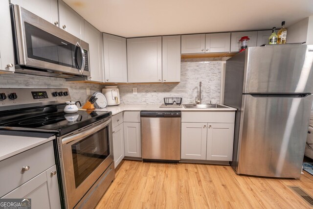 128 Branch St, Toccoa, GA 30577 - kitchen featuring appliances with stainless steel finishes, a sink, light countertops, gray cabinetry, and light wood-style floors