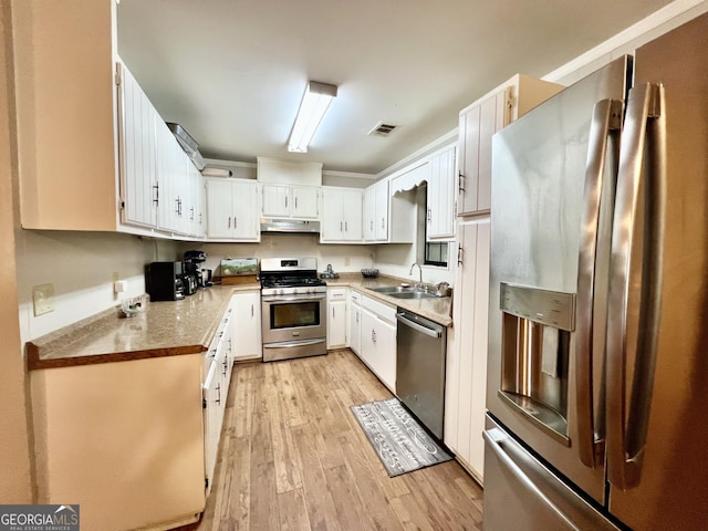 2618 Ga Highway 86, Adrian, GA 31002 - kitchen featuring appliances with stainless steel finishes, light wood-type flooring, under cabinet range hood, a sink, and white cabinets