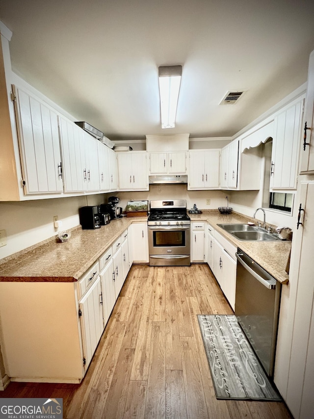 2618 Ga Highway 86, Adrian, GA 31002 - kitchen with stainless steel appliances, under cabinet range hood, a sink, light wood-style floors, and white cabinets