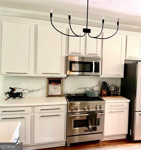 8525 Anchor On Lanier Ct, Gainesville, GA 30506 - kitchen with stainless steel appliances, light countertops, white cabinetry, tasteful backsplash, and wood finished floors