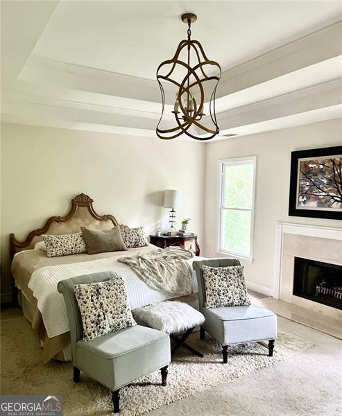 8525 Anchor On Lanier Ct, Gainesville, GA 30506 - bedroom featuring a tray ceiling, crown molding, a chandelier, and a tiled fireplace